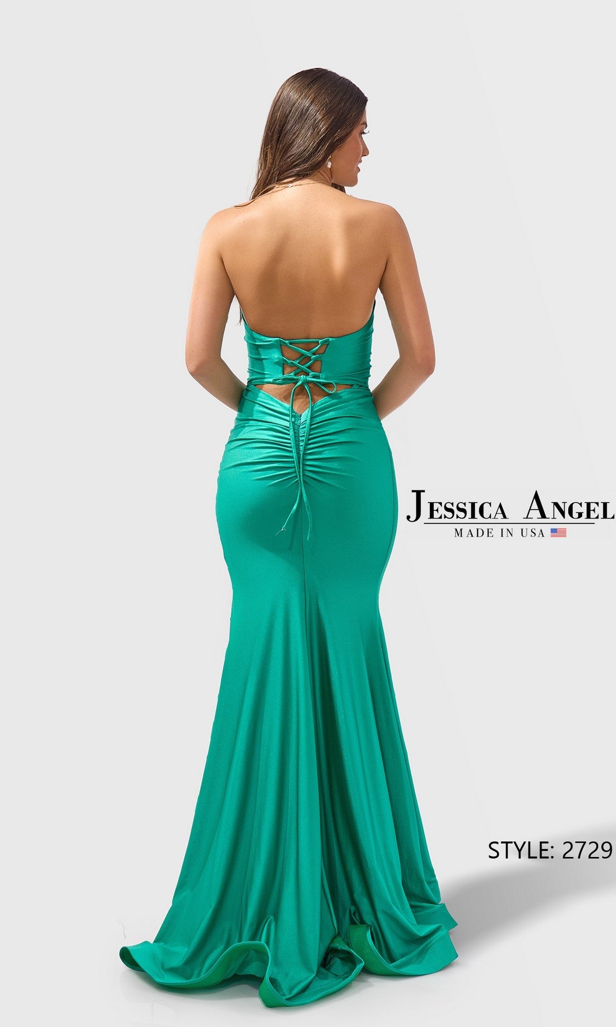 Woman wearing Long Prom Dress: Jessica Angel 2729, an emerald green satin-jersey, strapless floor-length gown with a lace-up back and ruched detailing, standing against a plain background.