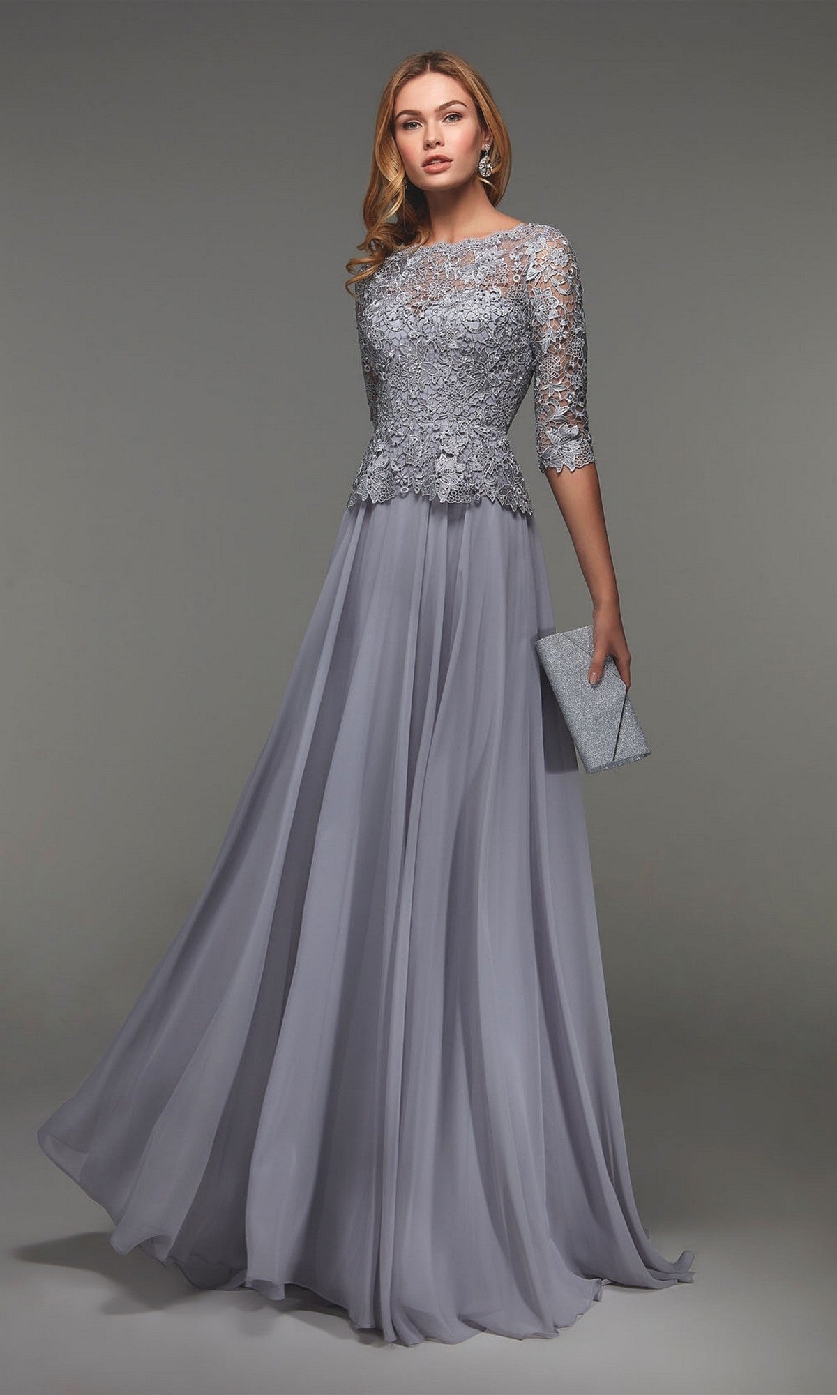 A woman in the Alyce 27470 long formal dress in silver, featuring a lace bodice and three-quarter sleeves, holds a matching clutch against a neutral background.
