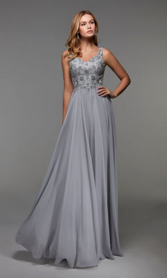 A woman poses against a plain gray background in the Alyce 27473 long formal dress. The sterling chiffon A-line gown, featuring an embellished bodice and flowing skirt, adds elegance to her graceful look.