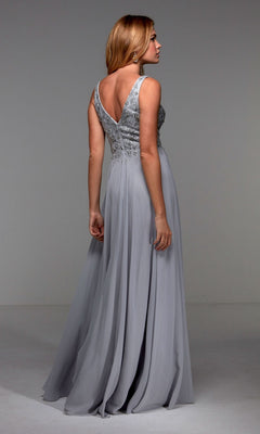 Woman models the Alyce 27473, a sleeveless, floor-length silver chiffon A-line dress with a deep V-back and flowing skirt, standing with her back to the camera.