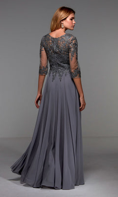 A woman stands facing away in a plain studio, wearing the Alyce 27474 long formal dress—a gray floor-length gown with an embellished bodice and lace detailing on the upper bodice and sleeves.