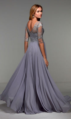 Woman wearing the Alyce 27475 long formal dress—light lavender, floor-length, with sheer lace sleeves and a low back—stands looking over her shoulder. An elegant option for formal events or as a mother-of-the-bride dress.