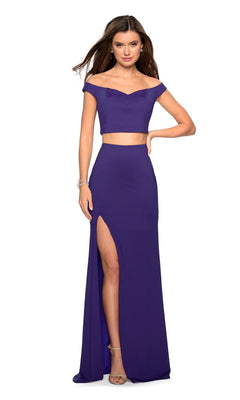 Woman wearing the La Femme 27496: an off-shoulder, two-piece purple prom dress with a high slit, paired with heels and set against a white background.