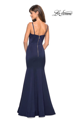 Woman wearing the La Femme Square-Neck Simple Long Prom Dress 27524 in navy blue, featuring a floor-length mermaid skirt, thin straps, and visible back zipper, standing with her back to the camera.