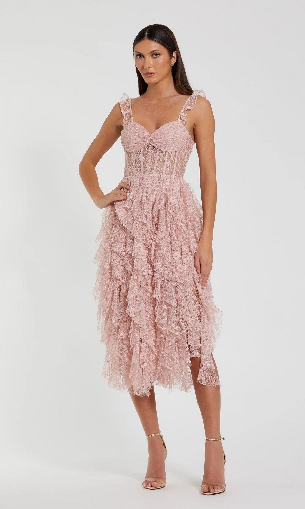 A woman wearing the Mac Duggal 27529 Midi Party Dress in blush, featuring lace ruffles, spaghetti straps, and a delicate corset bodice, stands against a plain white background.