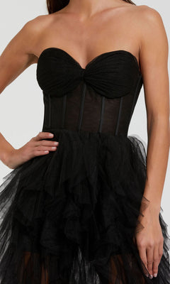 Woman wearing the Mac Duggal 27532 Strapless Ruffled Long Prom Dress, featuring a fitted bodice and layered tulle skirt, poses with one hand on her hip.