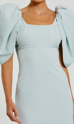 A person wearing the Mac Duggal 27534 Puff-Sleeve Long Formal Dress in light blue, featuring puffed short sleeves and a square neckline for an elegant evening gown look.