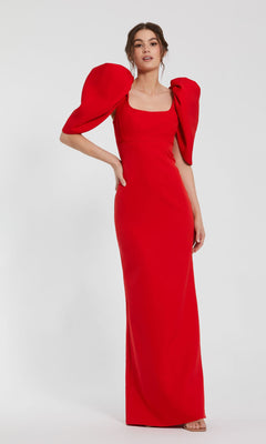 Woman wearing the Mac Duggal 27534 Puff-Sleeve Long Formal Dress, a fitted, floor-length red gown with bold puff sleeves, standing against a plain white background.