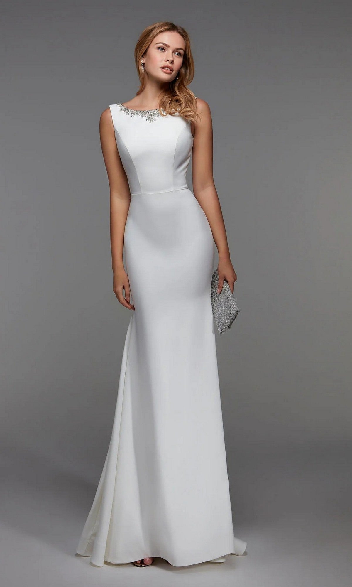 A woman stands against a plain gray background wearing the Alyce 27538 long diamond white sleeveless formal dress with an embellished neckline, holding a silver clutch.