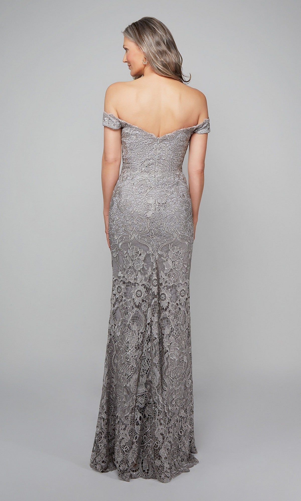 A woman models the Alyce 27553 long formal dress, featuring off-the-shoulder beaded lace in silver, floor-length, with her back to the camera against a plain background.