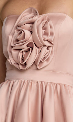 Close-up of the Mac Duggal 27554 High-Low Formal Dress in blush pink, featuring a strapless design with fabric roses adorning the bodice and a gathered skirt.
