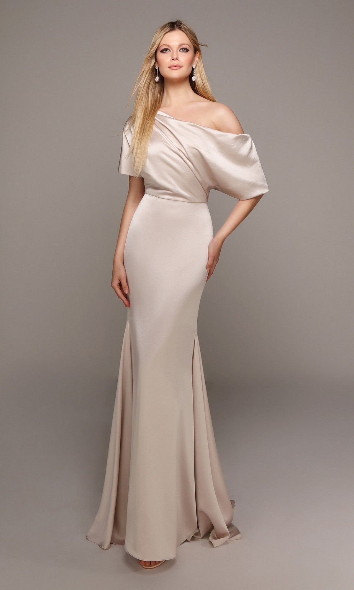 A woman poses elegantly against a plain gray background in the Alyce 27560, a floor-length, off-the-shoulder satin formal dress in champagne.
