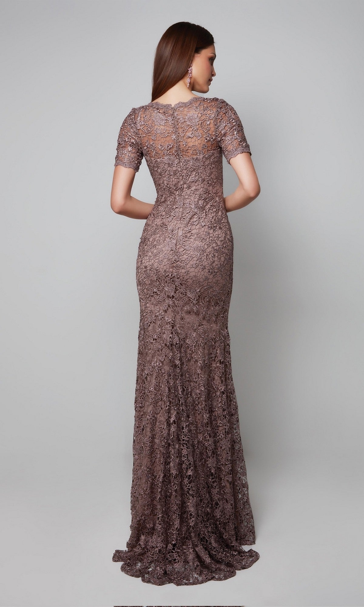 A woman stands with her back to the camera in the Alyce 27561 long formal dress—a floor-length, short-sleeved, fitted lace gown in muted brown, ideal as an elegant mother-of-the-bride option.