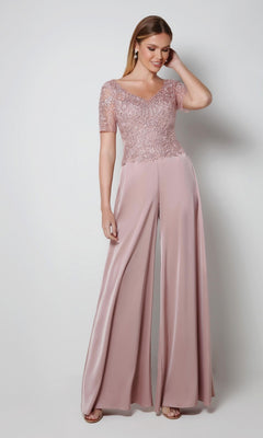 Woman smiling with one hand in her hair, wearing the Alyce 27564 long formal dress in Cashmere Rose—an elegant choice for the mother of the bride, featuring an embroidered bodice, against a plain light background.