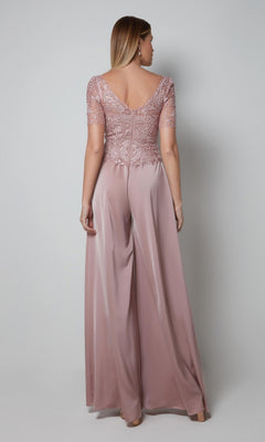 A woman faces away in the Alyce 27564 long formal dress—featuring an embroidered bodice, pink satin fabric, short lace sleeves, V-shaped back, and wide-leg pants—ideal for a mother of the bride, against a plain light background.
