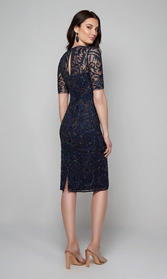 A woman in the Alyce 27583 knee-length semi-formal dress, featuring navy blue sheer sleeves and beaded detailing, stands in heels with her back to the camera.