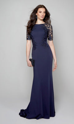 A woman wearing the Alyce 27585 long formal dress with a lace bodice and sleeves holds a black clutch, standing against a plain light gray background.