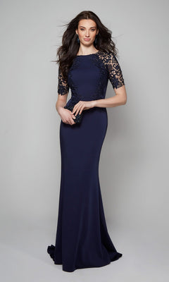 A woman models the Alyce 27585, a navy blue floor-length sheath formal dress with lace sleeves, holding a small black clutch against a light gray background.