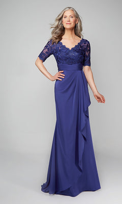 A woman wearing the Alyce 27595 long formal dress in navy, featuring a lace bodice, short sleeves, and floral appliqué details, stands against a plain light gray background.