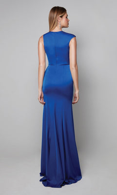 A woman faces away, modeling the Alyce 27598 long formal dress—a royal blue column silhouette with a fitted bodice and gentle flare—against a plain gray background.