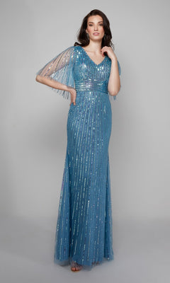 A woman poses in the Alyce 27599, a long formal beaded sequin dress in blue with vertical detailing, sheer short sleeves, and a V-neckline—an elegant mother-of-the-bride gown set against a plain background.