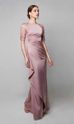 A woman stands against a plain gray background wearing the Alyce 27601 long formal dress in heather, featuring sheer embroidered short sleeves and ruched detailing—an ideal choice for a mother-of-the-bride.