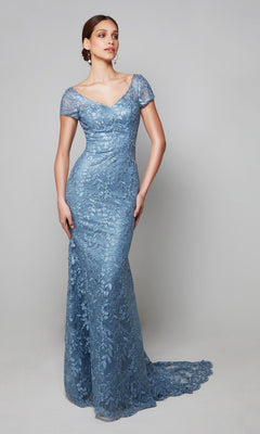 A woman in an Alyce 27602 Long Formal Dress, French Blue, fitted and floor-length with short sleeves and a slight train, stands against a plain light gray background.