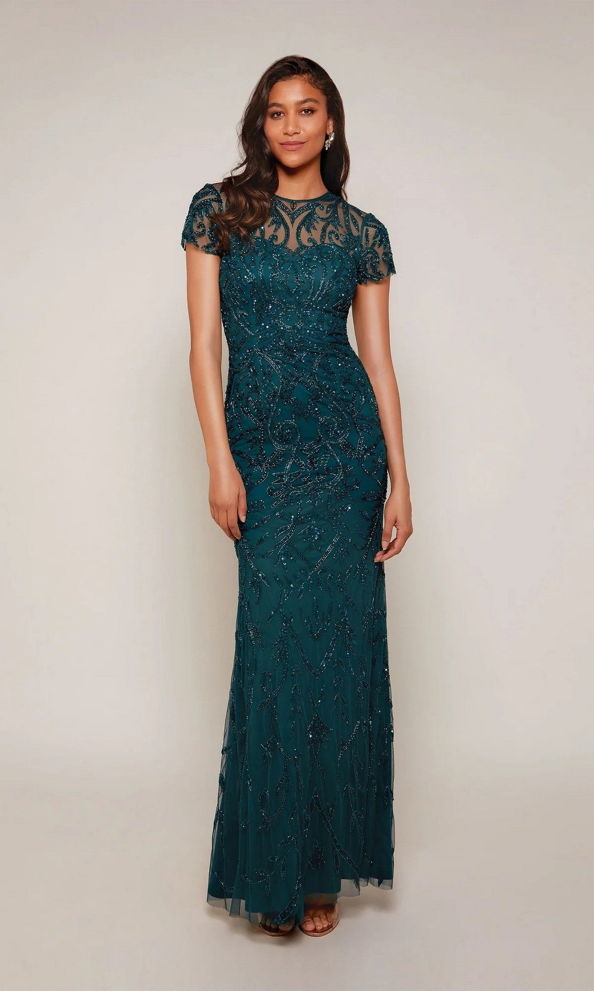 A woman poses against a plain light background in the Alyce 27607 long formal dress in midnight, featuring intricate beadwork and a sheer neckline.