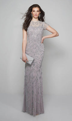 A woman poses against a light gray background in the Alyce 27607 long formal dress, silver/lilac, floor-length with short sleeves. She holds a silver clutch, her wavy hair and drop earrings finishing the elegant look.