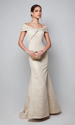 A woman in the Alyce 27613 long formal dress, sterling/gold color, holds a small clutch and stands gracefully against a plain light gray background.
