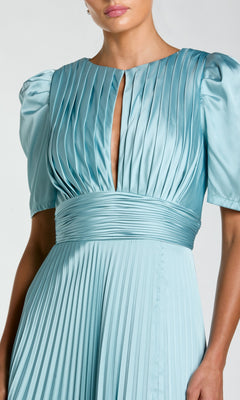 A woman wears the Mac Duggal 27616 long formal dress in light blue, featuring short puffed sleeves, a pleated skirt, waistband, and a small keyhole neckline.
