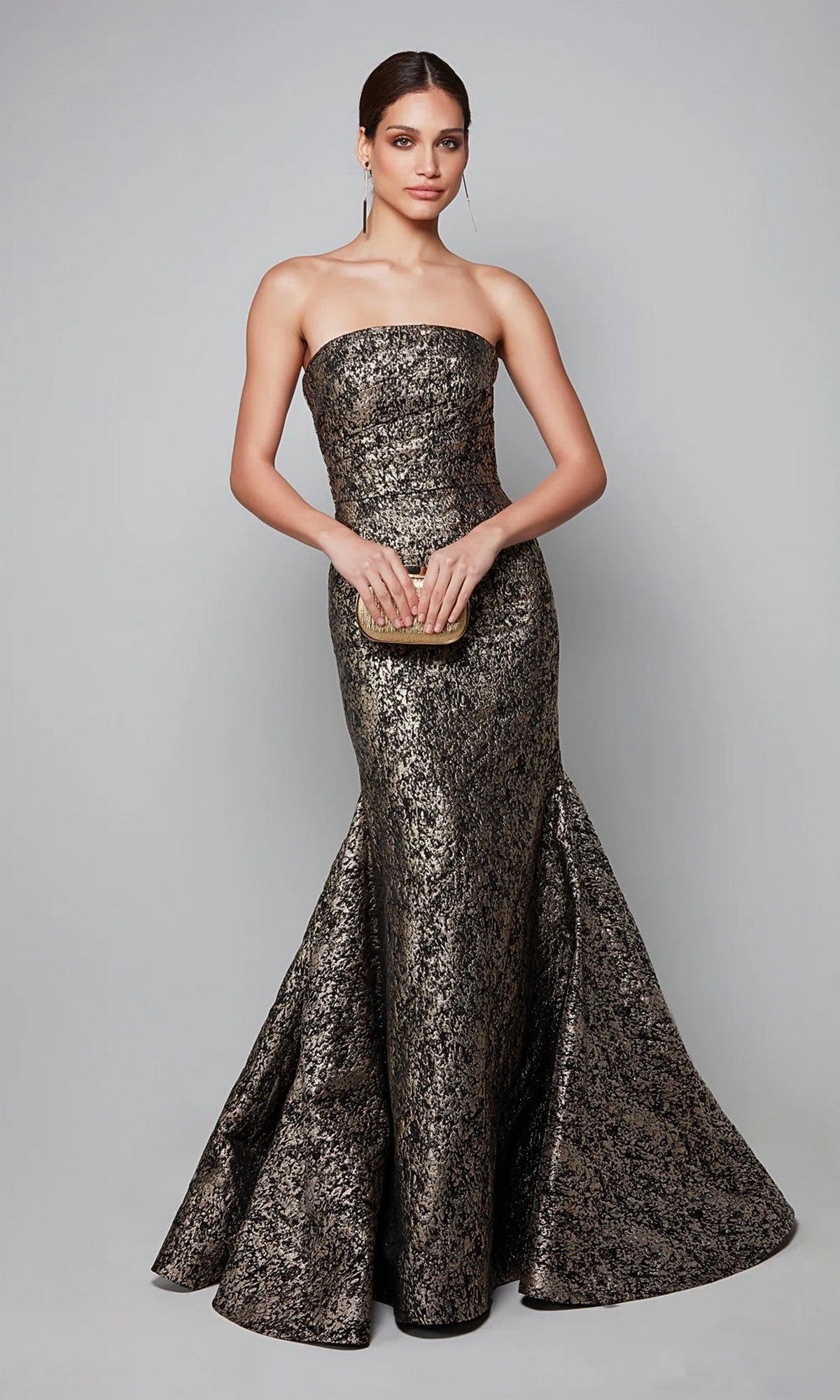 Woman wearing the Alyce 27621 Long Formal Dress, a strapless jacquard gown with a mermaid silhouette, holds a small clutch against a plain gray background for an elegant formal evening look.