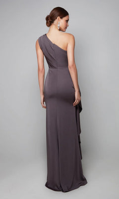 A woman models the Alyce 27624 long formal dress, standing with her back to the camera to highlight the gown’s draped fabric and side detailing against a plain gray background.