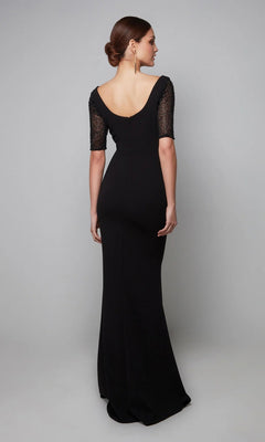 A woman faces away from the camera wearing the Alyce 27628 long formal dress—black jersey with short lace sleeves, a deep scoop back, and a thigh-high slit—set against a plain gray background.