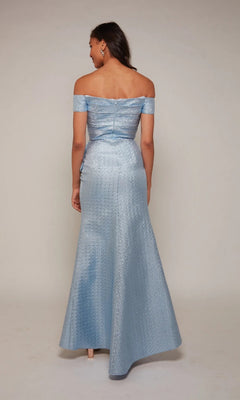 A woman stands with her back to the camera wearing the Alyce 27639 Long Formal Dress, a light blue, off-the-shoulder jacquard evening gown with a subtle textured pattern and floor-length elegance.
