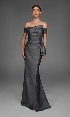 A woman wearing a floor-length, off-the-shoulder black Alyce 27639 formal dress with a side bow detail stands against a plain gray background.