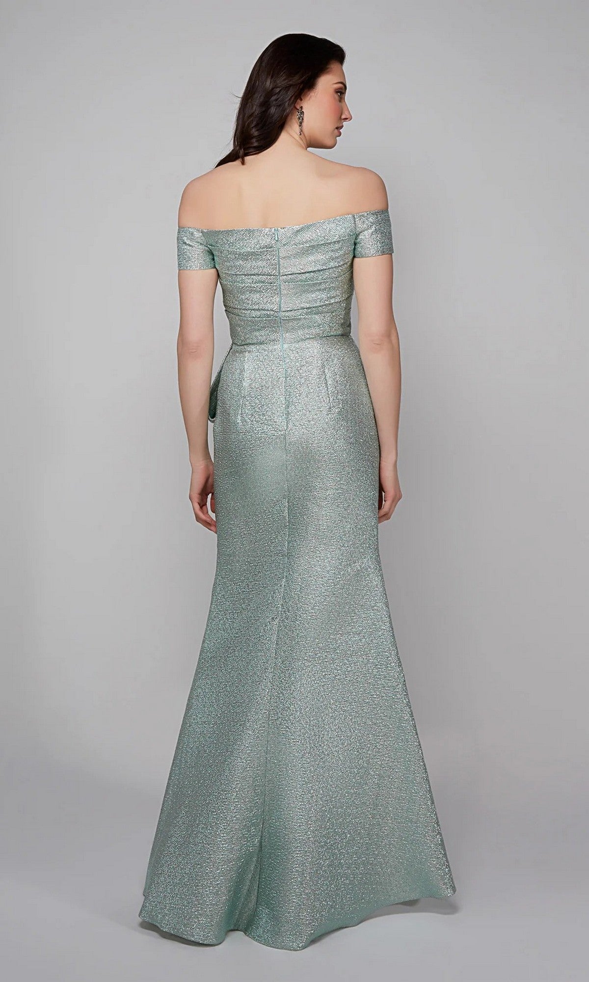 A woman faces away, wearing the Alyce 27639 long formal dress—a shimmering light green, off-the-shoulder gown with a fitted bodice and floor-length skirt.