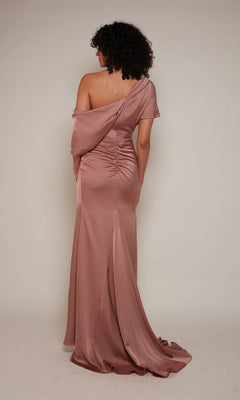 A person with curly hair faces away from the camera, modeling the Alyce 27652 Long Formal Dress—a floor-length, one-shoulder satin gown—against a plain background.