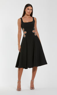 Woman wearing a black dress with floral embellishments on a white background