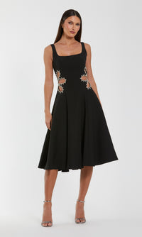 Woman wearing a black dress with floral embellishments on a white background