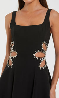 Black dress with cut-out designs and embellishments on a white background