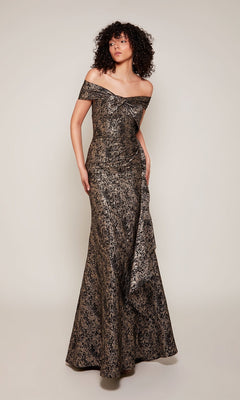 A person stands against a plain background wearing the Alyce 27667, a long formal off-the-shoulder metallic jacquard dress with a slight train—perfect for formal events or as a mother-of-the-bride gown.