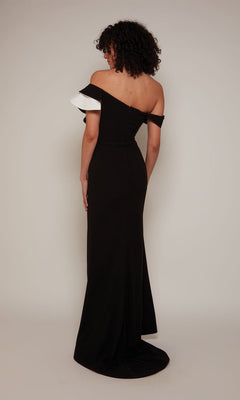 A person, facing away, wears the Alyce 27672 long formal dress—a fitted black sheath evening gown with off-the-shoulder styling and white detailing on one sleeve—posed against a plain light background.