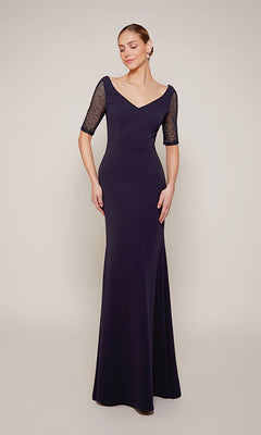 Woman in the navy Alyce 27677 long formal dress with sheer lace half sleeves, perfect for black-tie events or as a striking mother-of-the-bride look, standing against a plain light background.