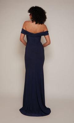 Person wearing the Alyce 27680 long formal dress in navy, featuring a slim fit and off-the-shoulder style, stands with their back to the camera against a plain background.