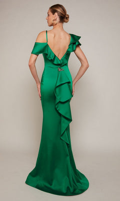 A woman stands with her back to the camera, wearing the Alyce 27691 long formal dress—a floor-length, off-the-shoulder green satin gown with a deep V-back and cascading ruffle detail.