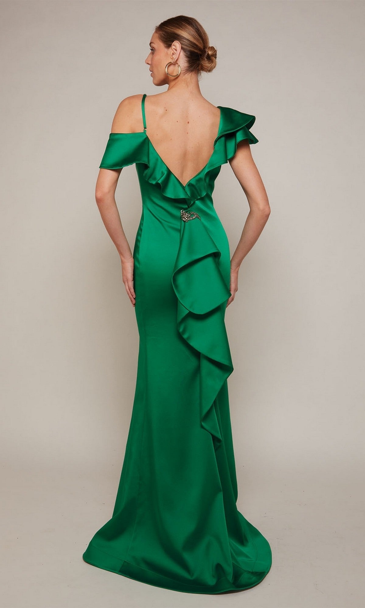 A woman faces away from the camera against a neutral background, wearing the Alyce 27691 long formal dress—an off-the-shoulder green satin evening gown with ruffle detailing down the back.