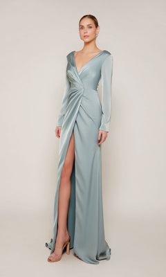 A woman wears the Alyce 27694, a long formal sage green satin dress with long sleeves, a deep V-neckline, and a high front slit—an elegant mother-of-the-bride choice against a plain background.