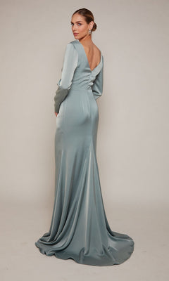 Wearing the Alyce 27694, a long formal dress in light blue satin with long sleeves and an open back, a woman stands against a plain background—an elegant mother-of-the-bride look.