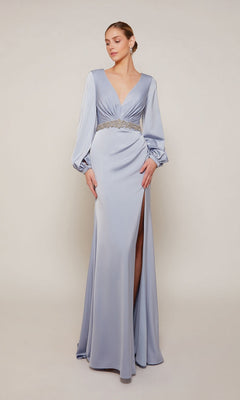 A woman wears the Alyce 27696 long formal dress in French Blue, featuring long sleeves, a deep V-neckline, jeweled waistband, and high slit, standing against a plain background.